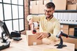 © Krakenimages.com - Young hispanic man ecommerce business worker packing cardboard box at office