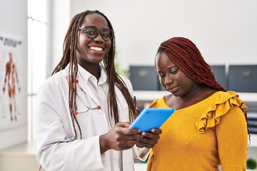 Poster - African american women doctor and patient using touchpad having consultation at clinic