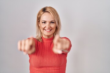 Canvas Print - Blonde woman standing over isolated background pointing to you and the camera with fingers, smiling positive and cheerful