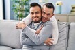 © Krakenimages.com - Two men couple hugging each other sitting on sofa at home