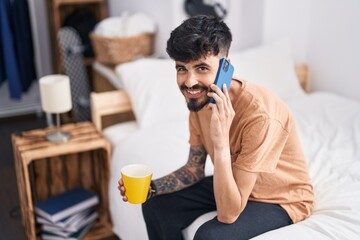 Sticker - Young hispanic man talking on smartphone drinking coffee at bedroom