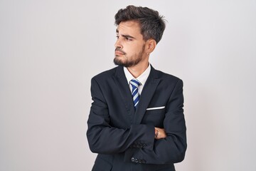 Poster - Young hispanic man with tattoos wearing business suit and tie looking to the side with arms crossed convinced and confident