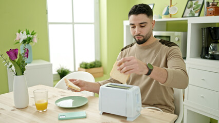 Wall Mural - Young arab man having breakfast sitting on table at home