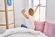© Krakenimages.com - Young blonde woman waking up stretching arms at bedroom
