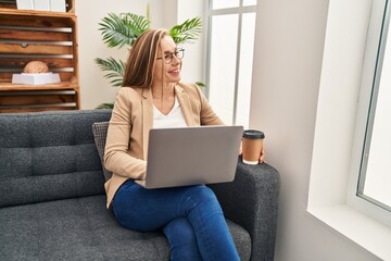 Wall Mural - Young blonde woman psychologist using laptop drinking coffee at psychology clinic