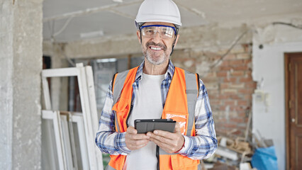 Sticker - Middle age man builder smiling confident using touchpad at construction site