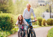 © Soloviova Liudmyla - Portraits Smiling father with daughter during summer outdoor bicycle riding. They enjoy togetherness in the summer city park. Happy parenthood and childhood or active sport life concept image.