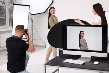 Poster - Professional photographer and assistant working with beautiful model in modern photo studio, selective focus