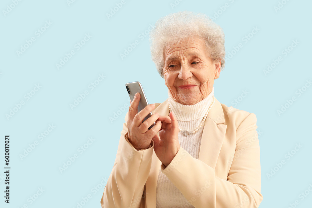 Senior woman using mobile phone on blue background