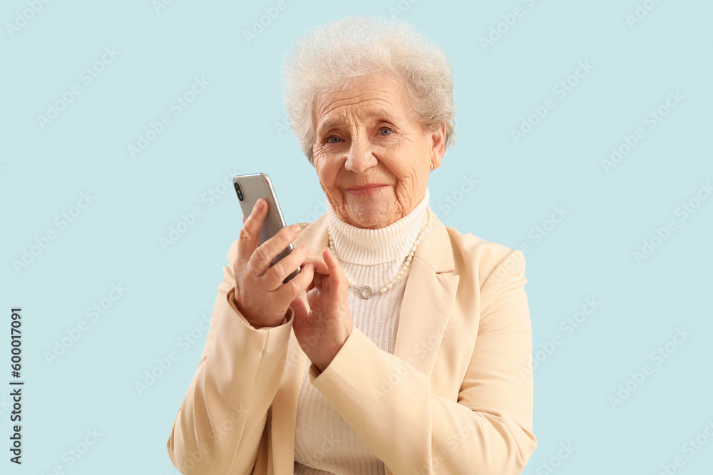 Senior woman using mobile phone on blue background
