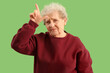 © Pixel-Shot - Senior woman showing loser gesture on green background