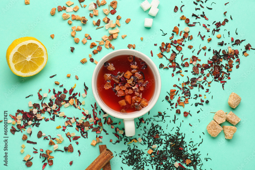 Composition with cup and heaps of dried fruit tea on turquoise background