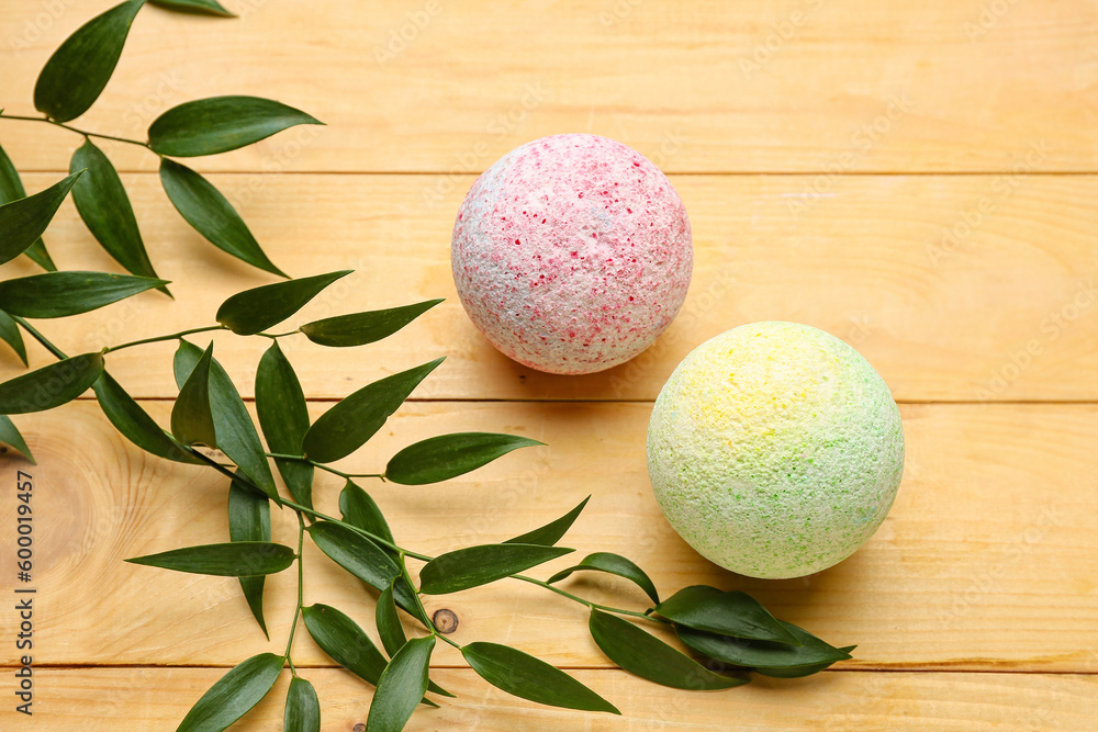 Bath bombs with plant branches on wooden background