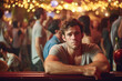 © wetzkaz - a sad young adult man is out and about, city or party or restaurant in the evening or at night, crowd of drunk people around and in the background. Generative AI
