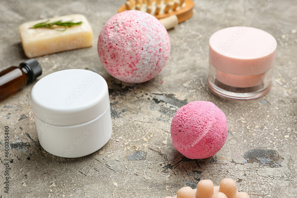 Bath bombs with jars of cream on grunge background, closeup