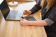 Kobieta licząca na kalkulatorze siedząca przy biurku