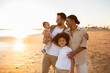 © Prostock-studio - Beachside bonding. Happy multiracial family walking and enjoying time together on beach during holidays