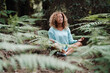 © simona - Health natural lifestyle meditation woman in the forest park with green tropical leaves all around. One healthy female people in yoga lotus position sitting on the ground in the woods. Wellbeing