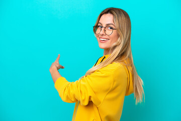 Sticker - Young Uruguayan woman isolated on blue background pointing back