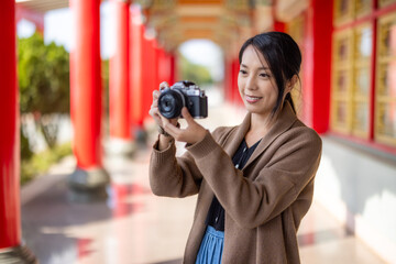 Wall Mural - Travel woman use digital camera to take photo in Chinese temple