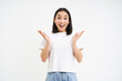 Enthusiastic asian woma, clap hands and smiles with surprised, happy face, congratulating, praising, standing over white background