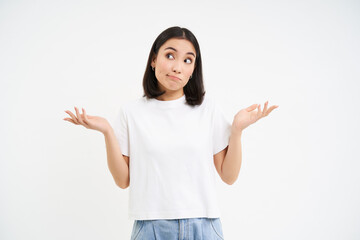 Wall Mural - Portrait of confused korean woman, shrugging shoulders, looks puzzled, dont know, has no idea, stands over white background