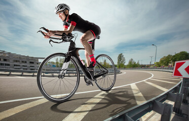 The cyclist rides on her road bike at suny day.