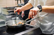 © pavel siamionov - man chef cooking fried salmon fish in frying pan on kitchen