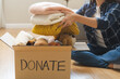 © KMPZZZ - Recycling, Donation for poor, asian young woman, girl sitting pack object at home, putting on stuff into donate box with second hand clothes, charity helping and needy people. Reuse recycle, moving.