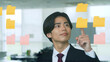 © metamorworks - オフィスで付箋を見ながら考えるビジネスマン