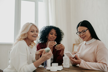 Sticker - Three happy mature women discussing beauty treatments while sitting at the desk together