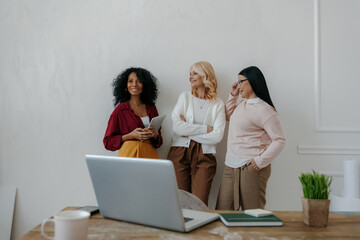 Sticker - Three mature women communicating and smiling while leaning on the wall in office