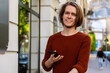 © _KUBE_ - Portrait of handsome young Caucasian smiling man holds smartphone. Summer street in background. Concept of online connection