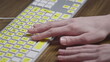 © Diflope - Close-up of a computer keyboard with braille. A blind girl is typing words on the buttons with her hands. Technological device for visually impaired people