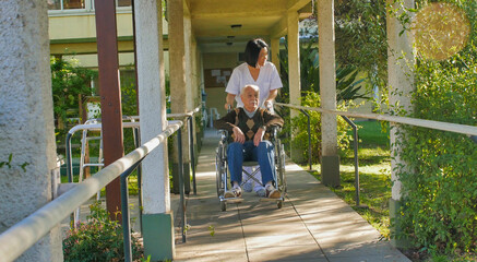 Sticker - Asian female doctor talking to elderly retired man on the wheelchair in the hospital yard. Happiness, rehabilitation and retirement concept