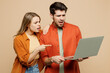 Young sad couple two friends family IT man woman wears casual clothes hold use work point finger on laptop pc computer together isolated on pastel plain light beige color background studio portrait.