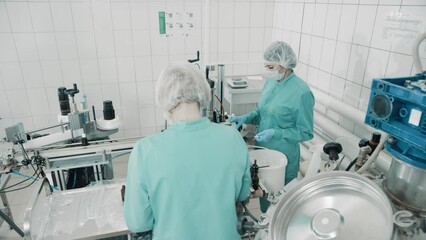 Wall Mural - 4K women work on the packaging line. Preparing bottles for use. Female health worker. Bottles on a conveyor belt. Production line of pharmaceutical manufacturing. Close up, DOF