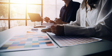 Close up ux developer and ui designer brainstorming about mobile app interface wireframe design on table with customer breif and color code at modern office.Creative digital development agency