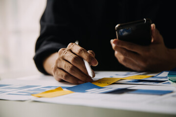 Close up ux developer and ui designer brainstorming about mobile app interface wireframe design on table with customer breif and color code at modern office.Creative digital development agency