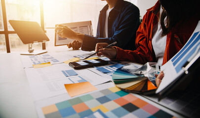 Close up ux developer and ui designer brainstorming about mobile app interface wireframe design on table with customer breif and color code at modern office.Creative digital development agency