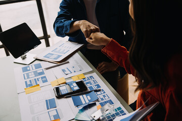 Close up ux developer and ui designer brainstorming about mobile app interface wireframe design on table with customer breif and color code at modern office.Creative digital development agency