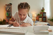 © DragonImages - Schoolgirl doing homework for math class at desk in her bedroom