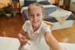 © DragonImages - Happy schoolgirl taking selfie at her desk when doing homework