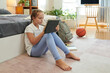 © DragonImages - Schoolgirl sitting next to her bed and drawing or writing on tablet computer