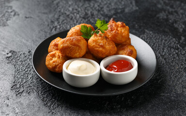 Wall Mural - Battered chicken balls with tomato ketchup, mayonnaise on black plate. Party food