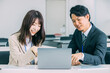 © Trickster* - パソコンを使いながら話す日本人のビジネスマン男女