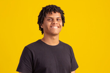 Young dark-skinned man with curly hair making facial expressions in studio photo.