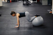 © Dusan Petkovic - A strong muscular sportswoman is doing fitness exercises with a ball in a gym.