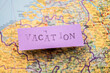 © Trygve - Vacation stencil text on purple paper over a map.
