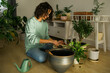 © satura_ - Woman grows potted plants at home watering and take care flowers - gardening and houseplant care concept